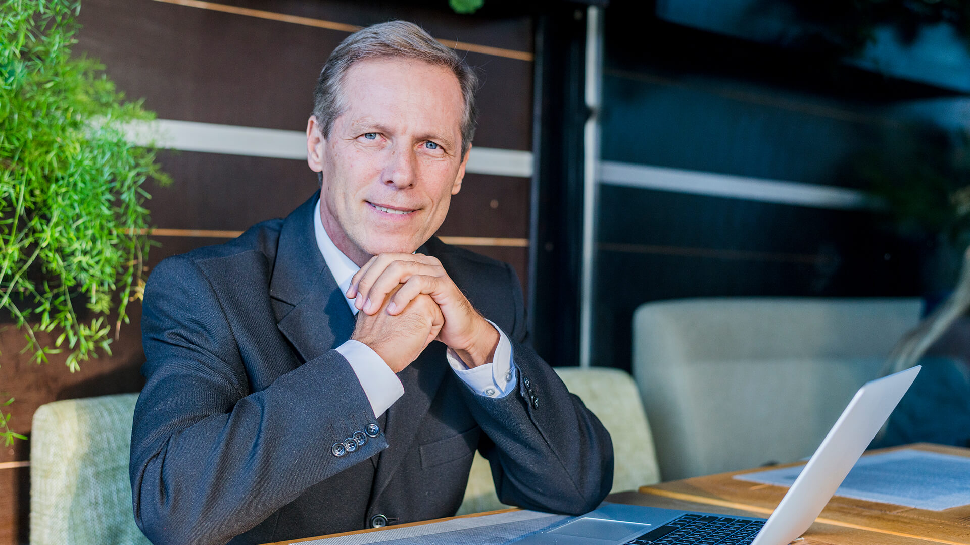 Portrait of a mature businessman founder with laptop over desk in restaurant